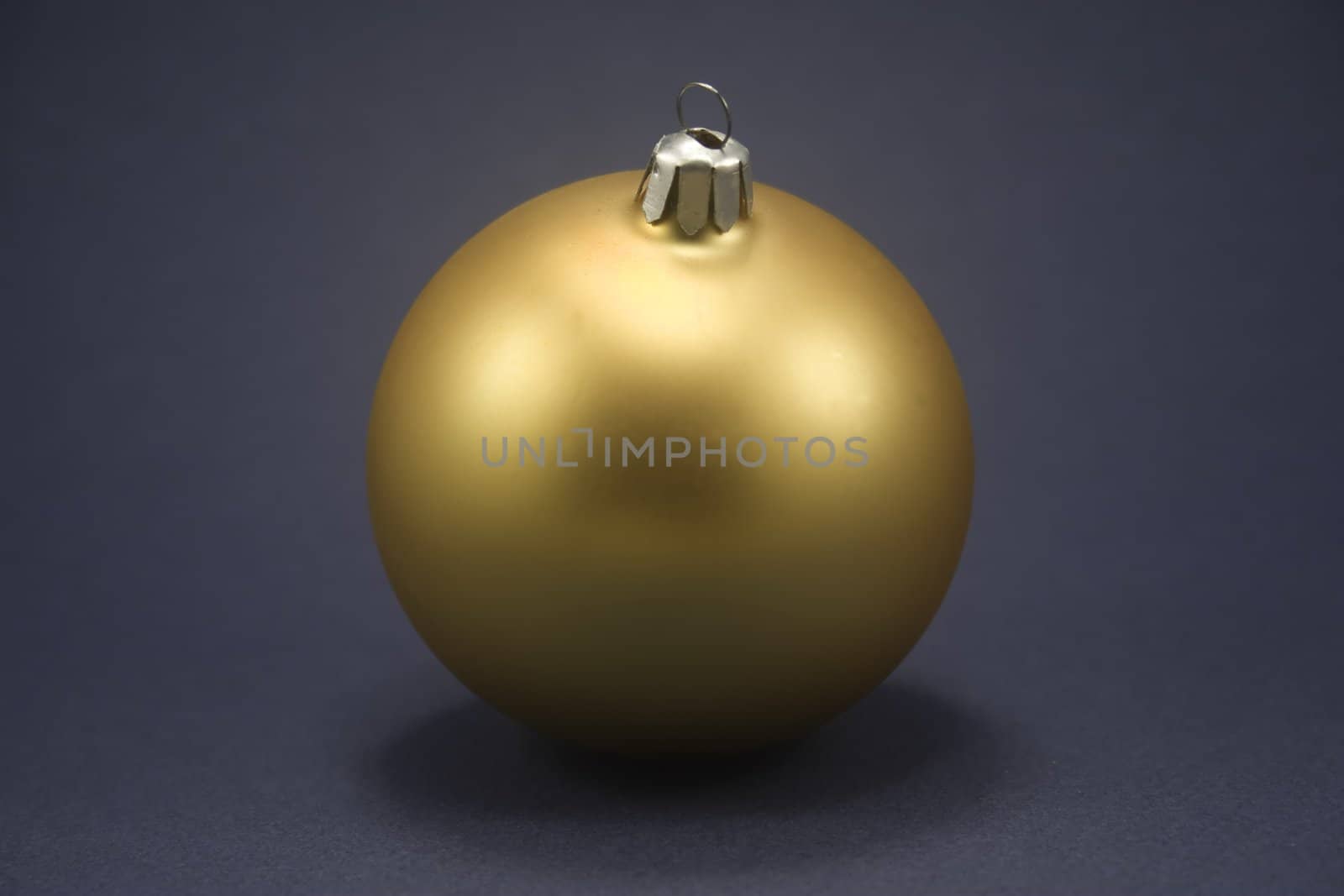 Single gold ornament isolated against blue paper
