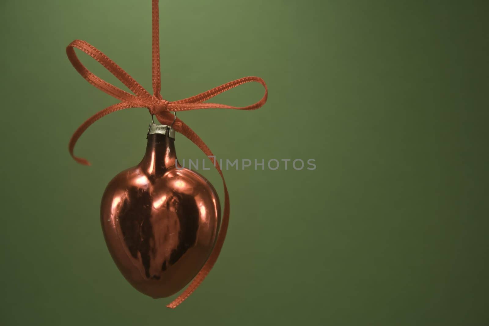 Single red heart ornament hanging isolated on green paper