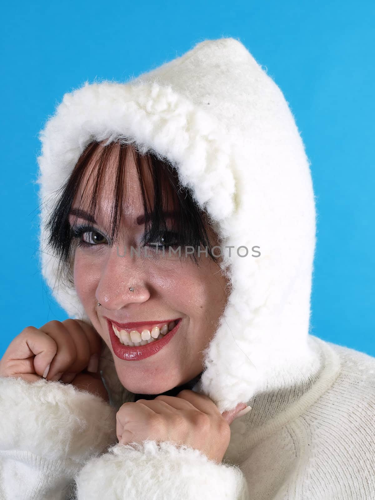 Beautiful brunette in a white hooded sweater, artificial snow falling down around her, against a blue background.