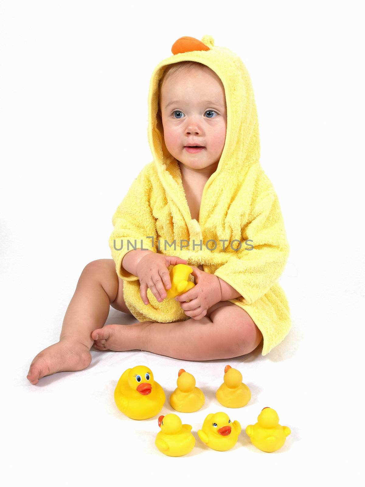 A female child wearing a yellow bathrobe plays with her rubber ducks.