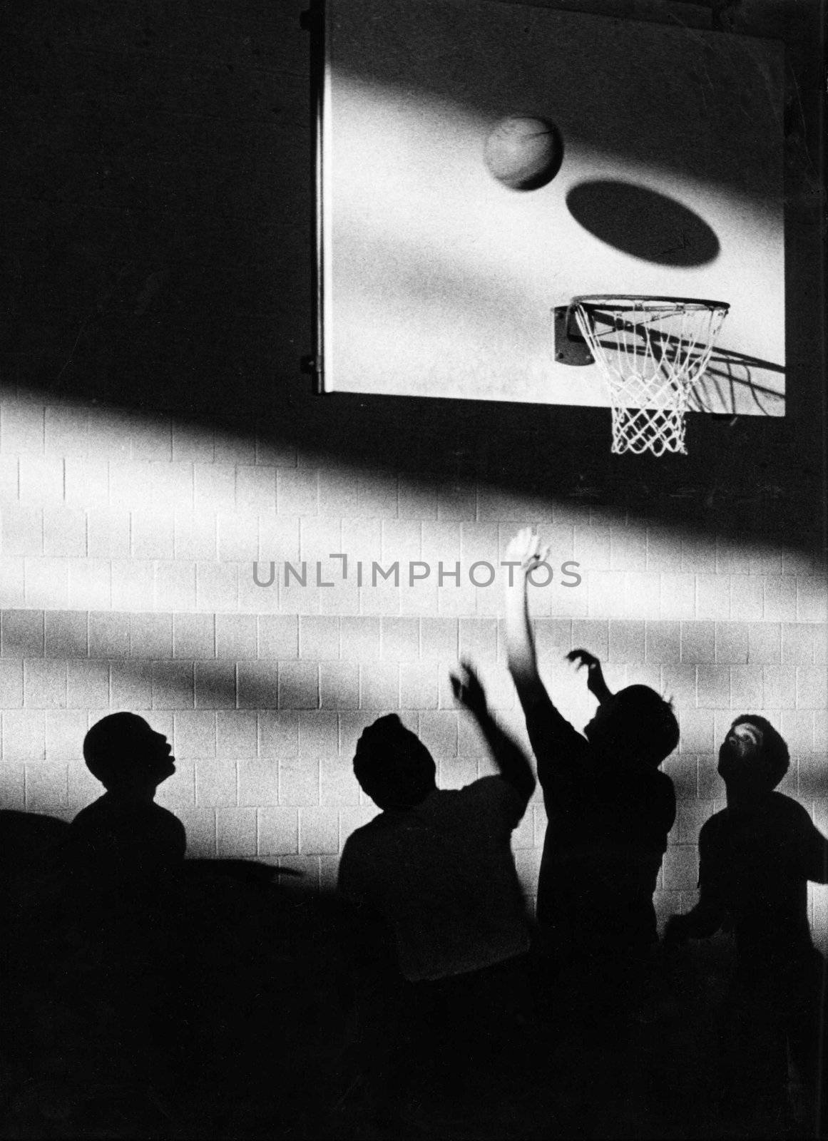 Young men playing basketball with a silhuette creating an artistic look.