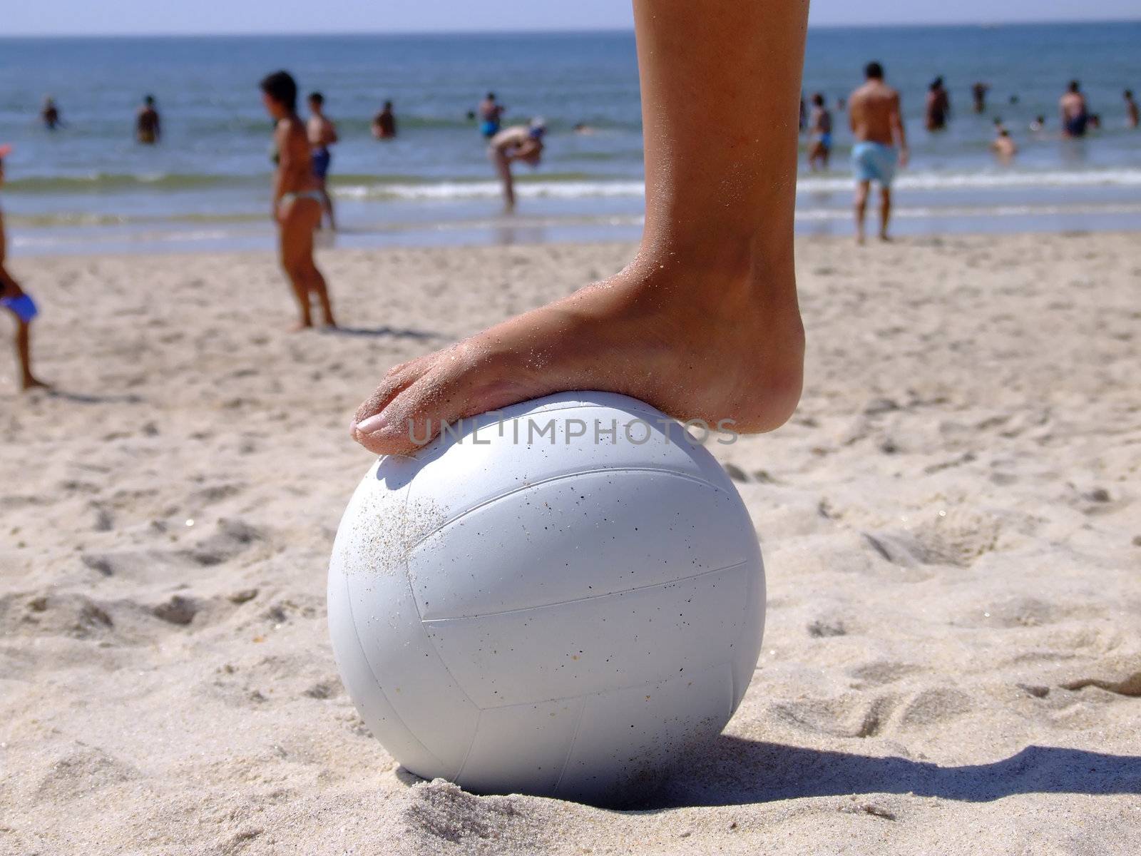 Woman foot on a volleyball on the sand