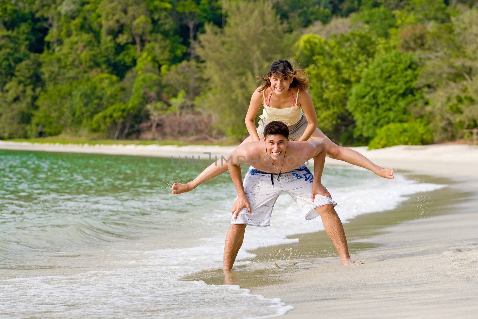 young woman and man playing leapfrog at the beach