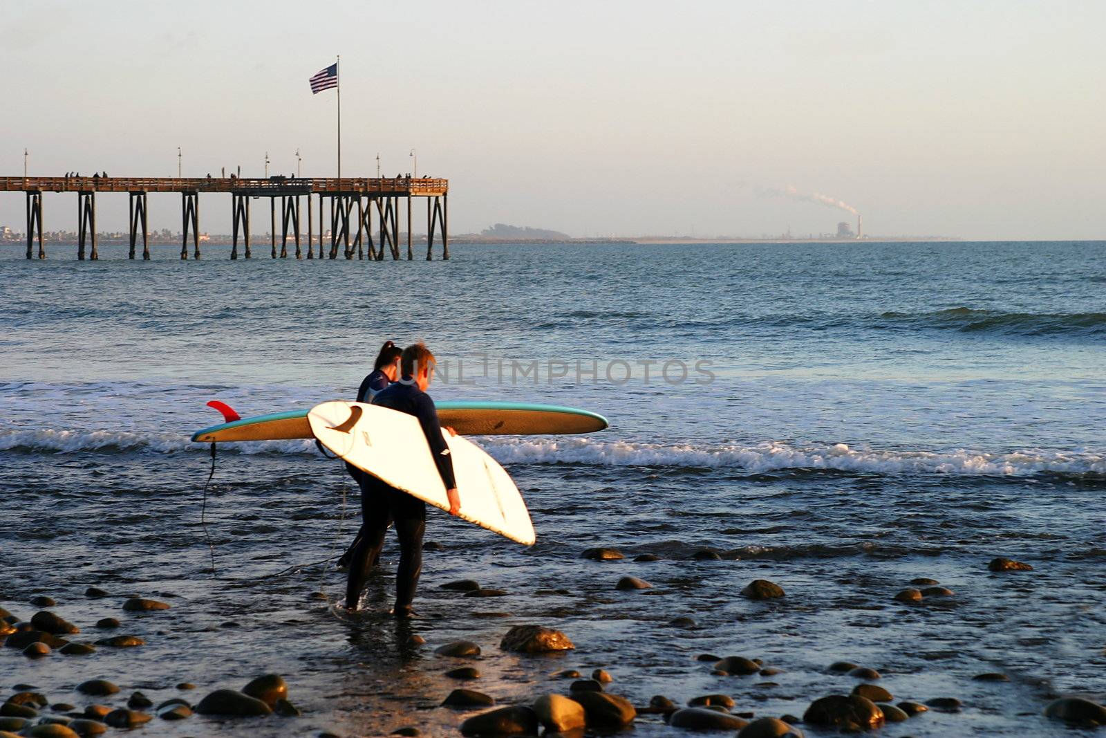 Surfer at sunset at the beach near the pier in Ventura California.