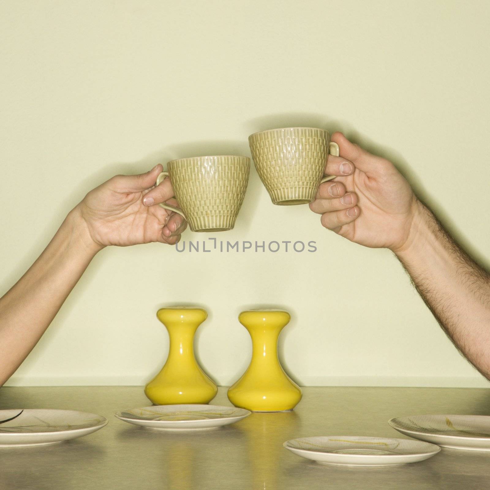 Hands toasting cups. by iofoto