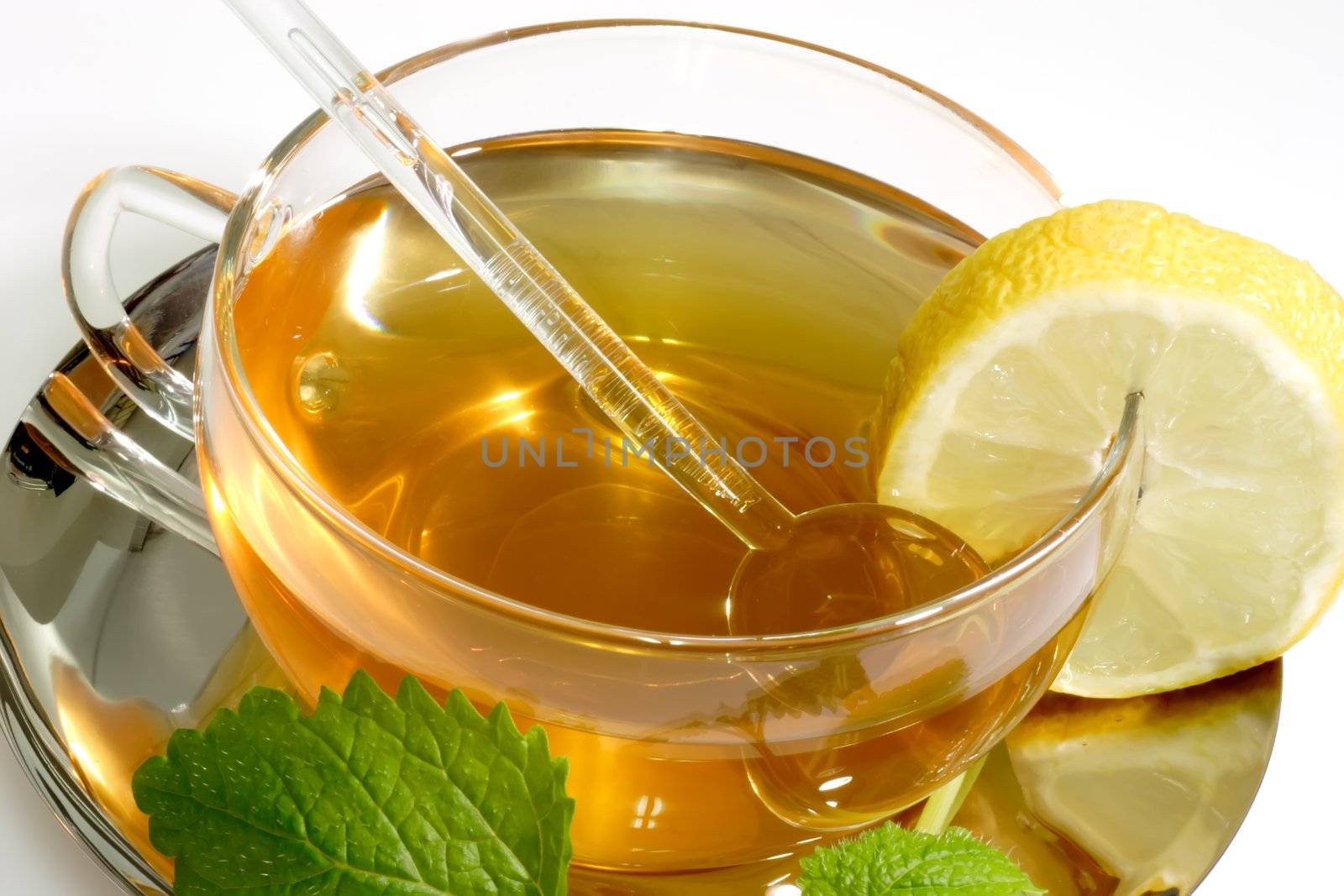 Lemon balm tea in a glass cup with garnish on light background