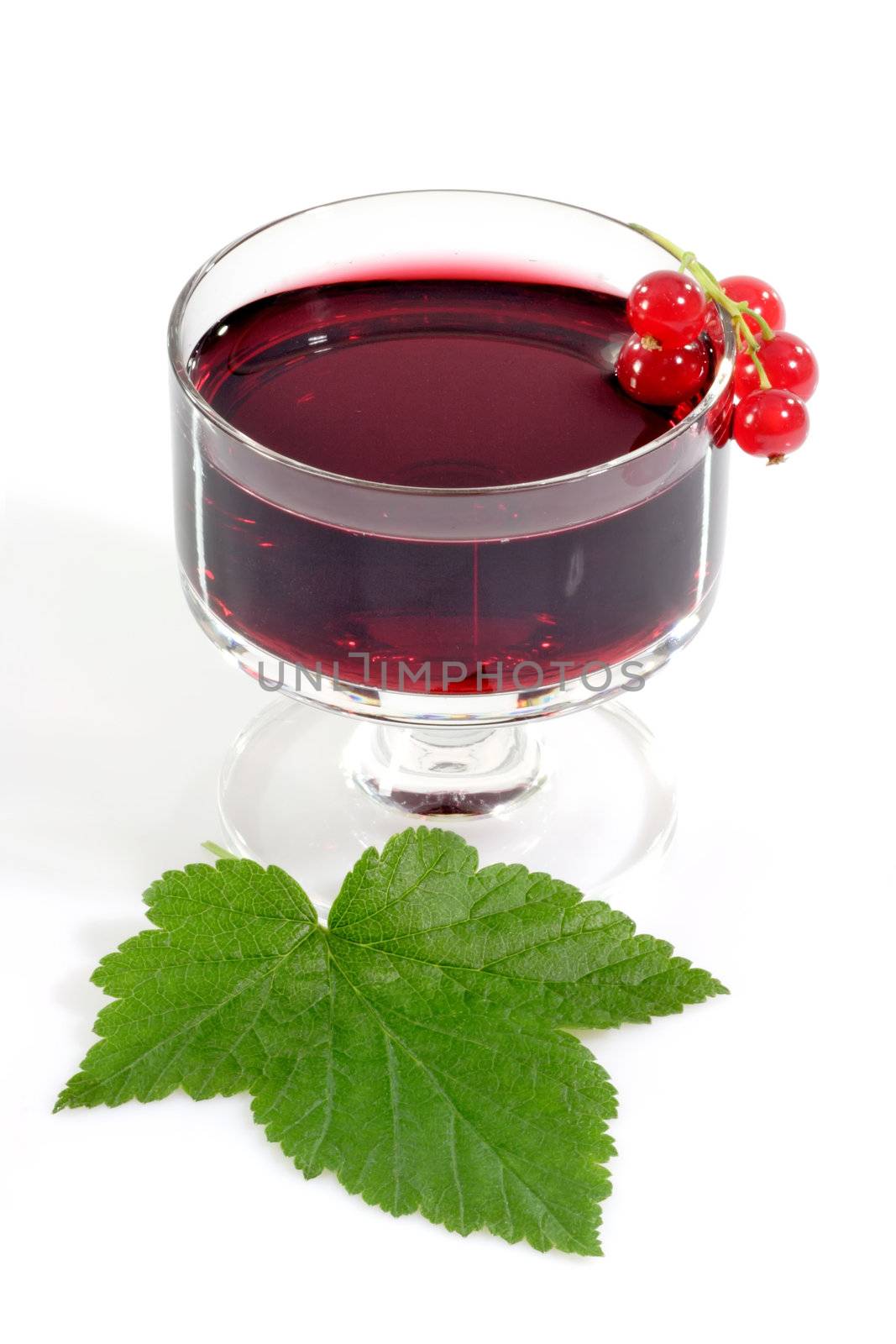 A glass of currant liqueur with garnish on light background
