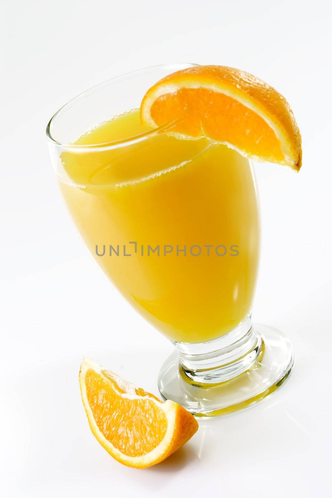 Glass of orange juice with garnish on light background