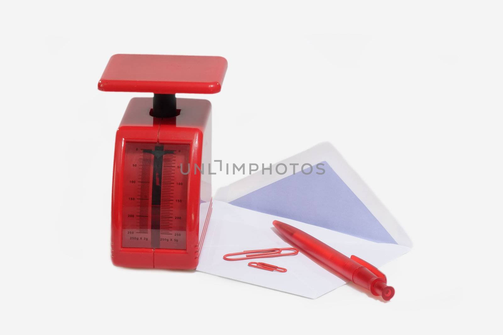 Red letter scale with envelope, ballpen and paper clips on bright background