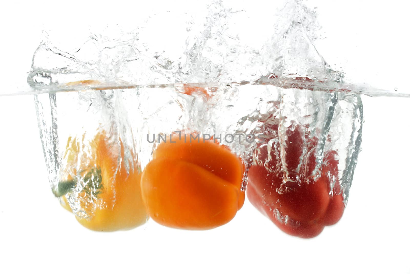 close-up three peppers falling in water, isolated on white