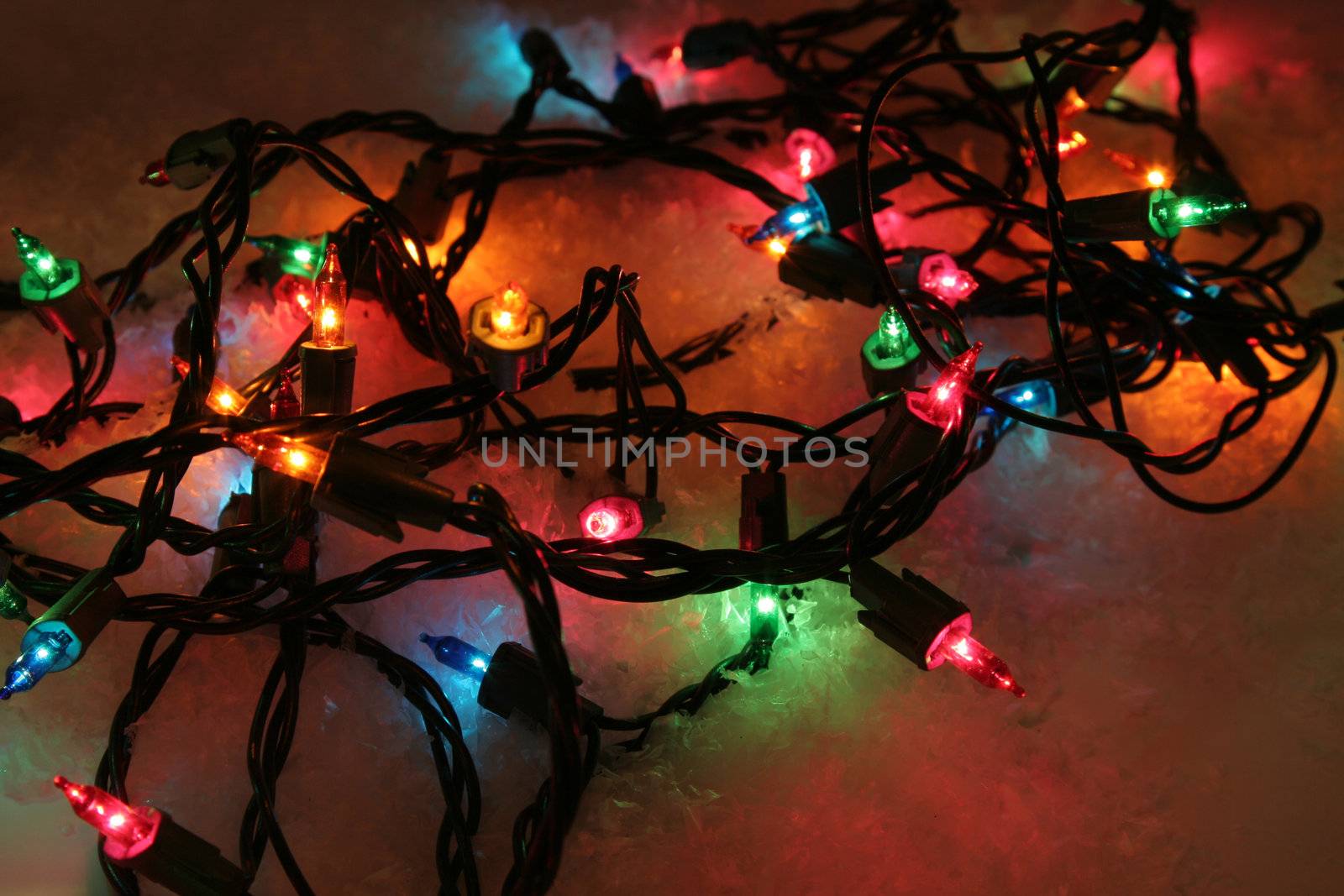 A bunch of multi-color Christmas lights sitting in snow.