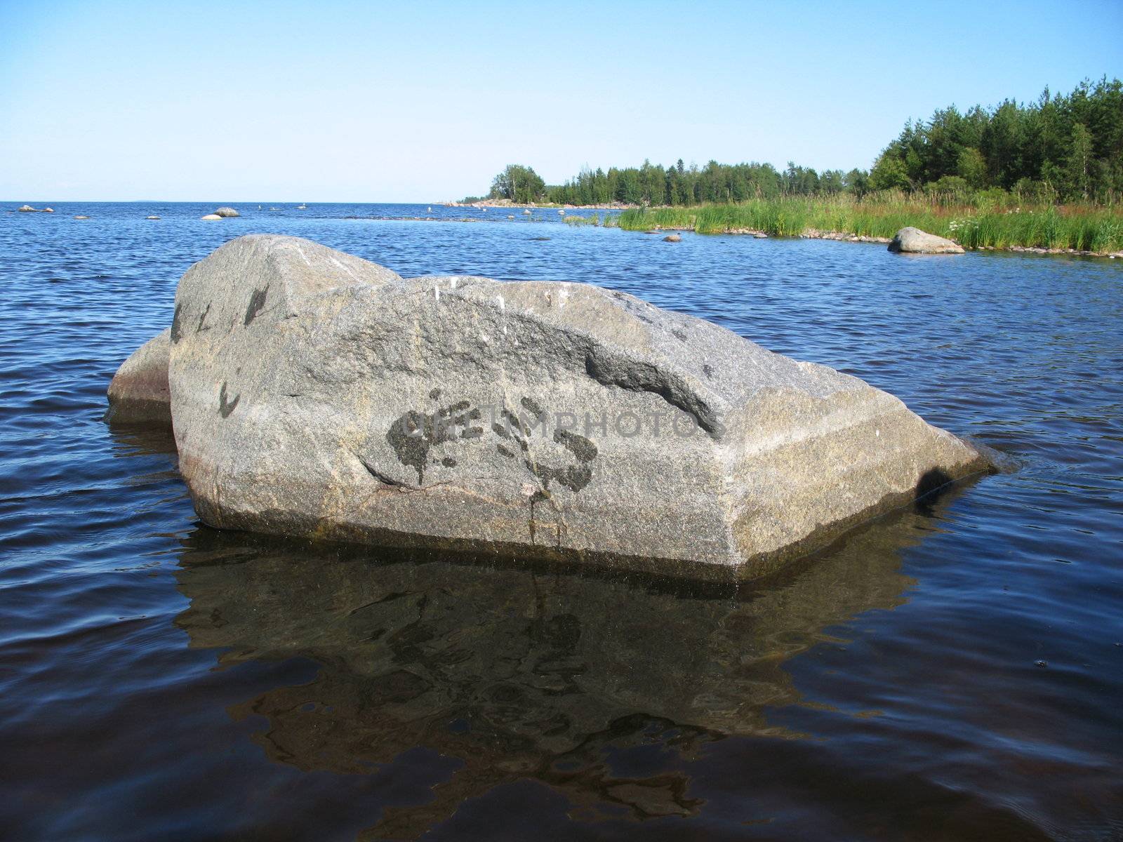 Wet handprint on the stone near lake coast