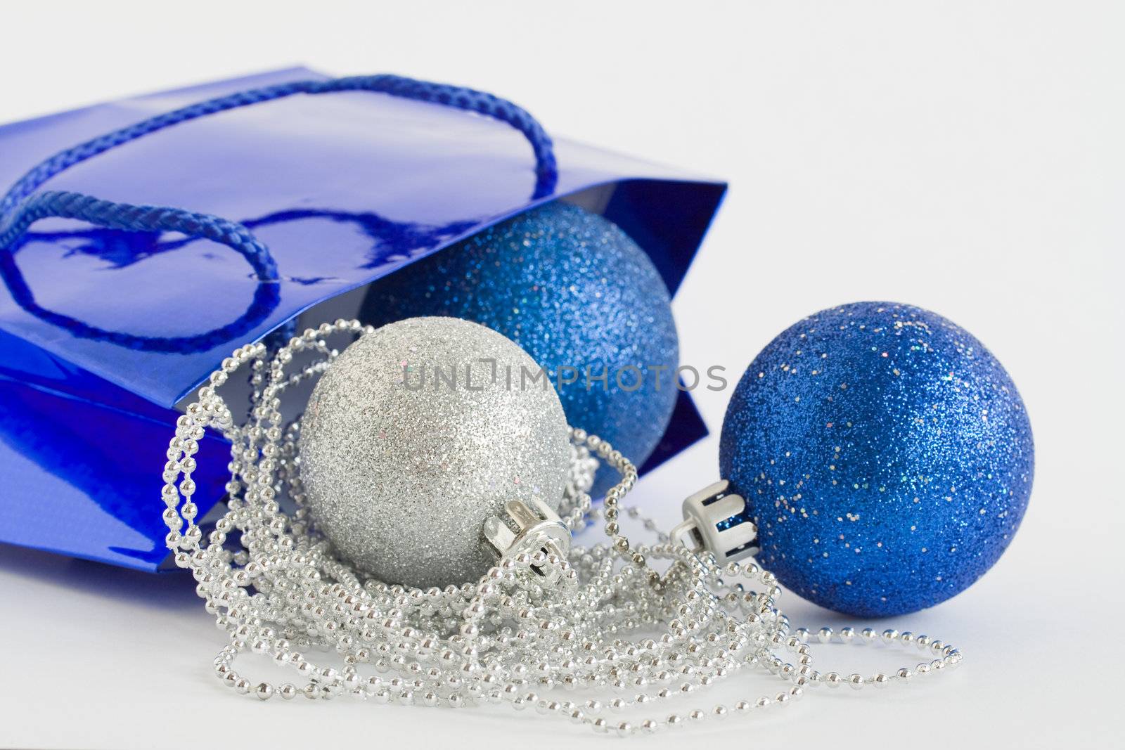 Blue bag, christmas balls and glass beads on white background