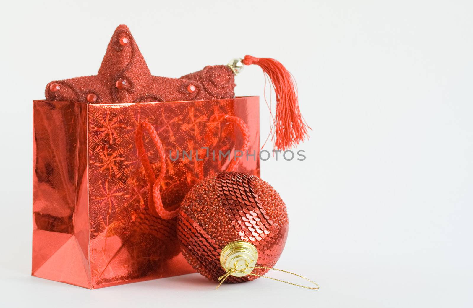 Red bag with handicraft christmas toys on white background. Focus on ball
