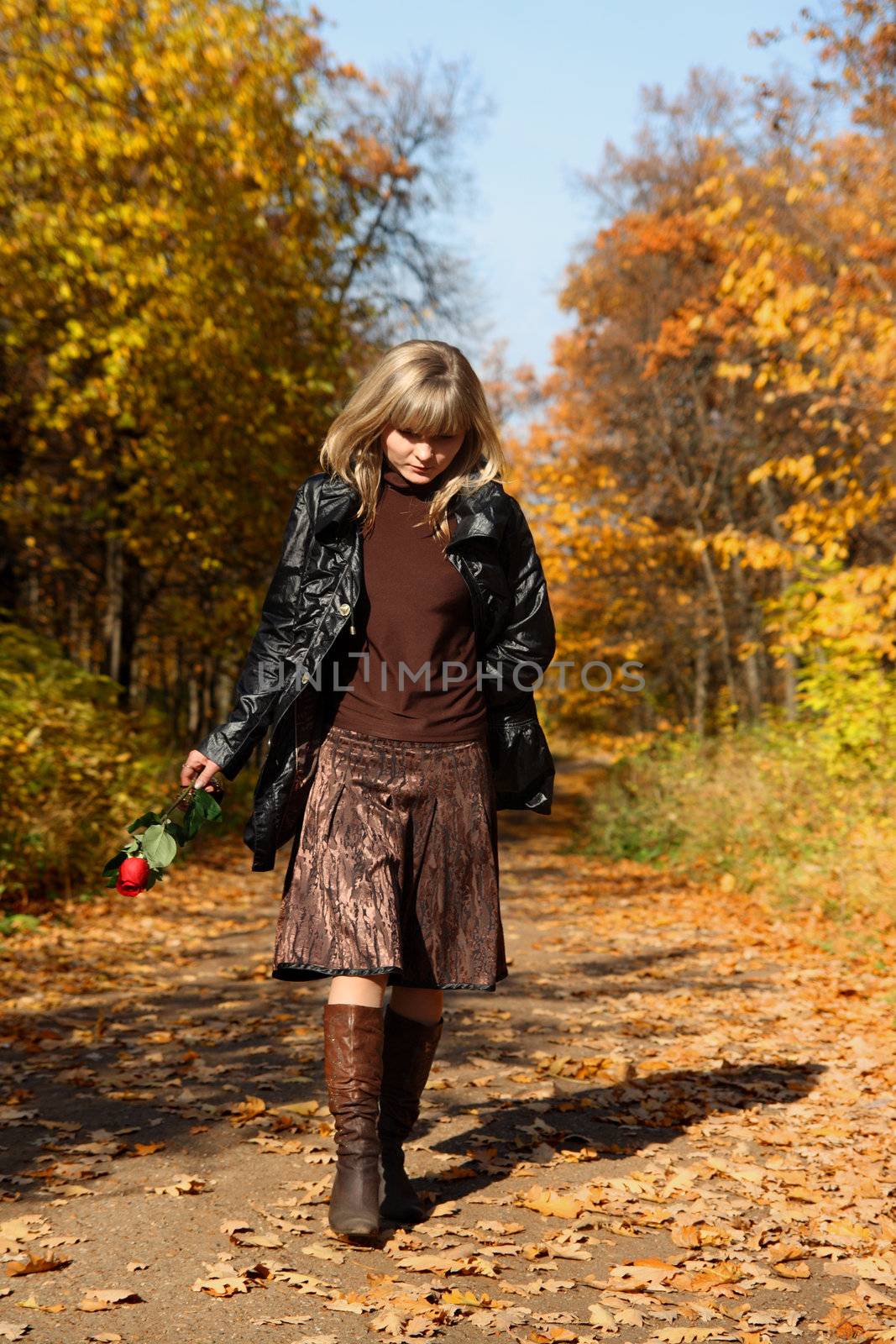 sadness girl with rose walking in autumn park