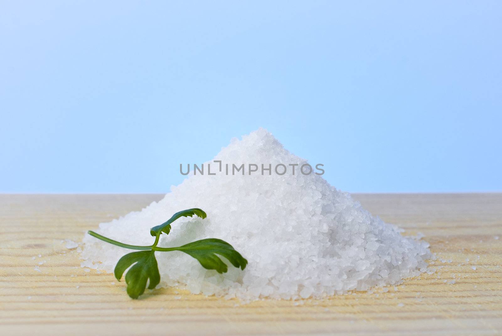 Sea salt and parsley on top of a wood table.