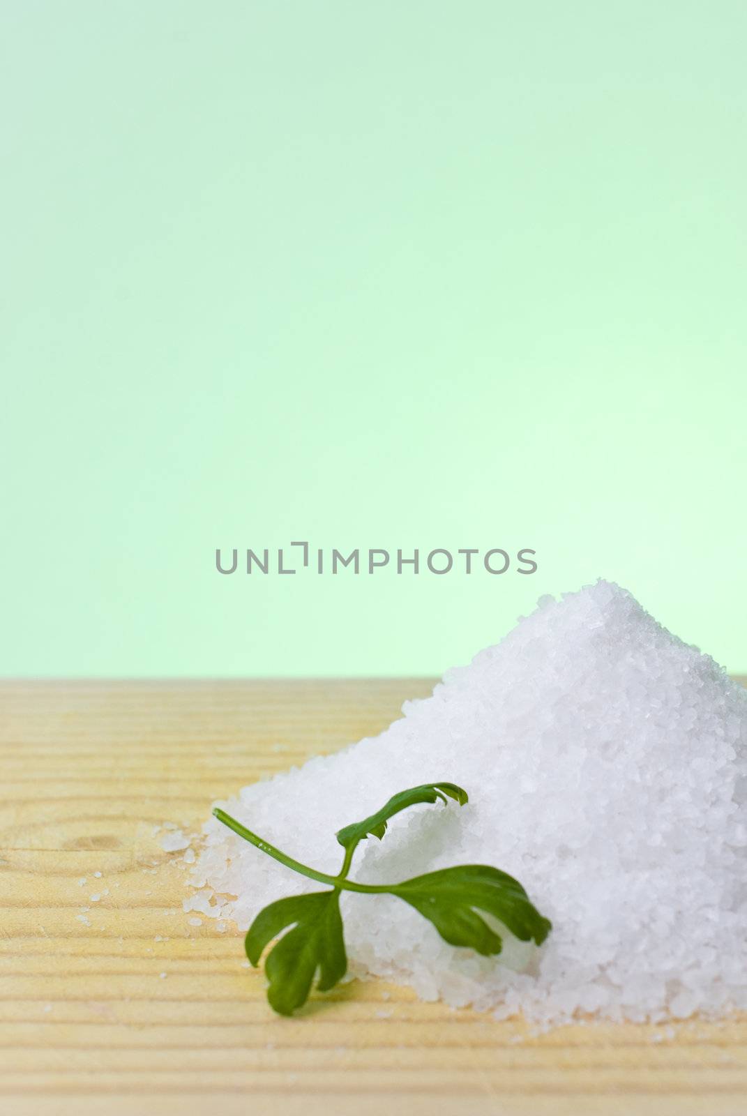 Sea salt and parsley on top of a wood table.