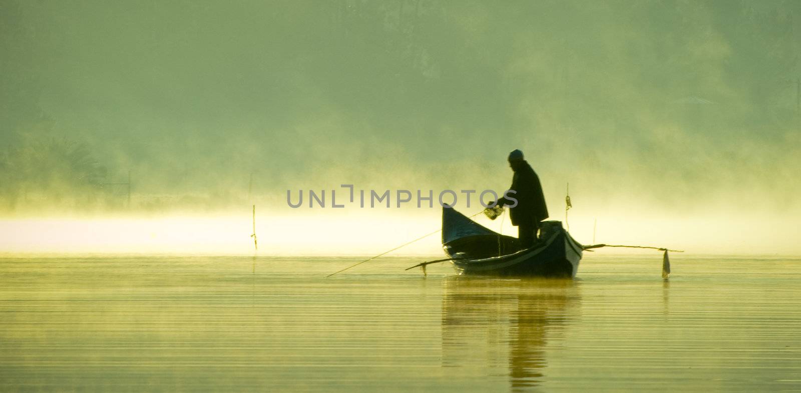 Landscape of a lake with the silhouette of a boat and a fisherman.