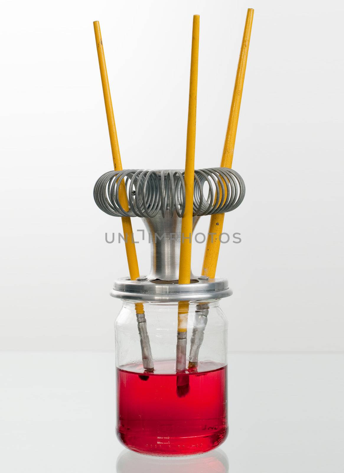 Three used paint brushes on a glass stand.