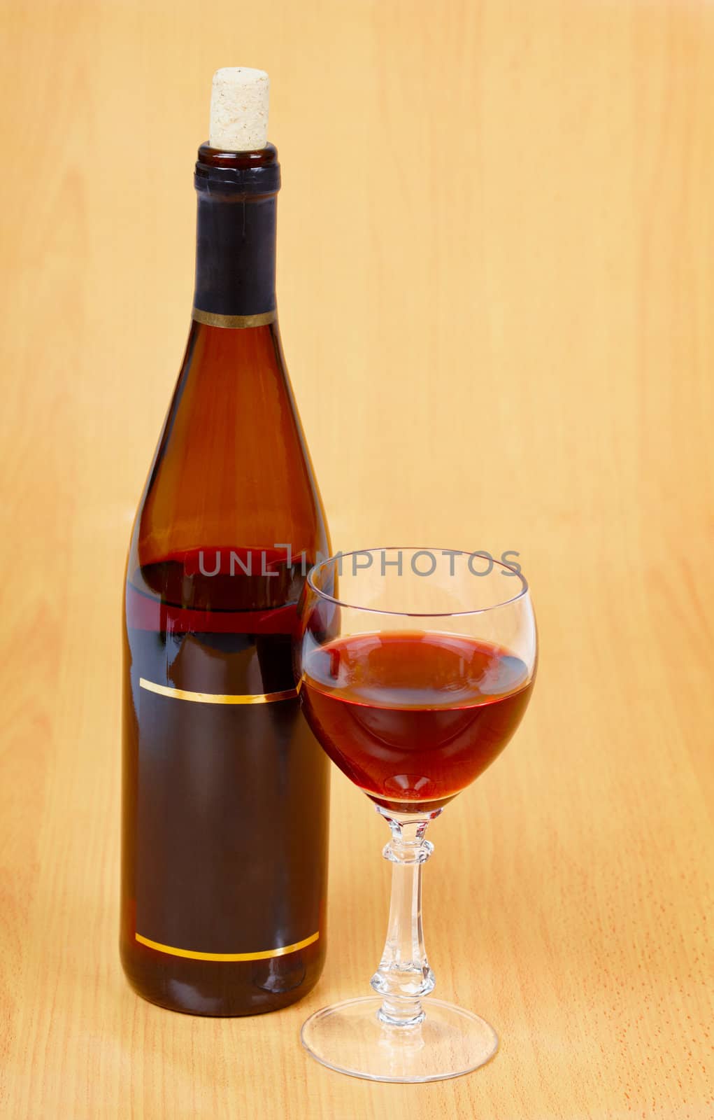 A bottle of red wine and a glass on a wooden table