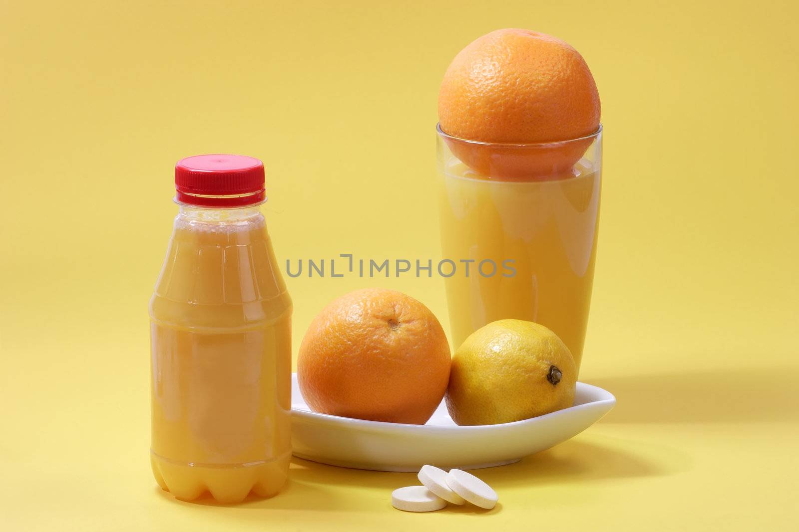 Orange juice with effervescent tablets with glass and fruits on yellow background