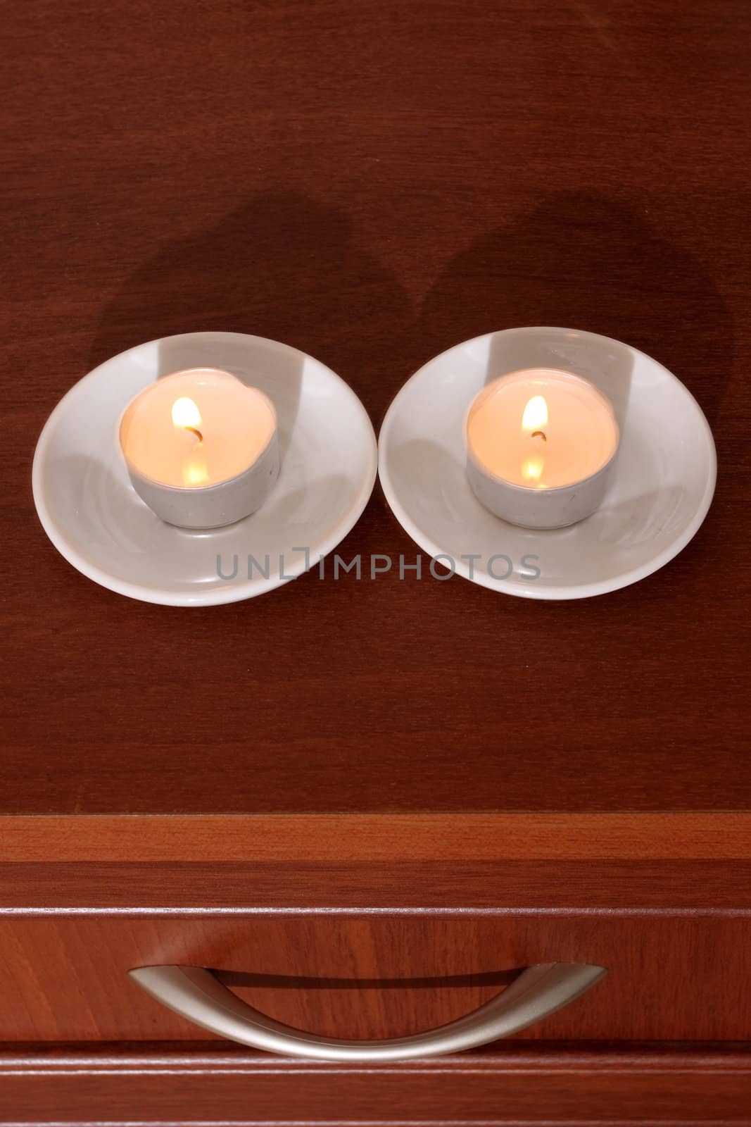 Two candles on a locker and the drawer handle form a smiling face