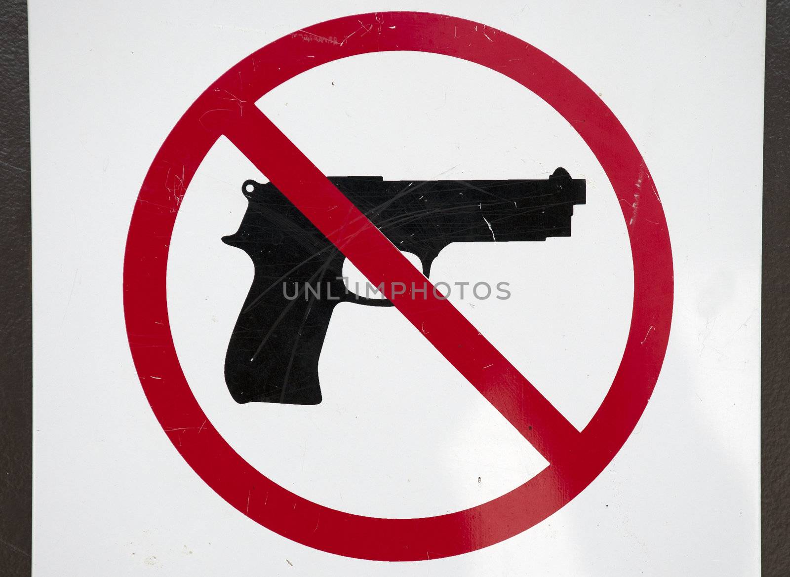 a scratched up no gun sign mounted on a door