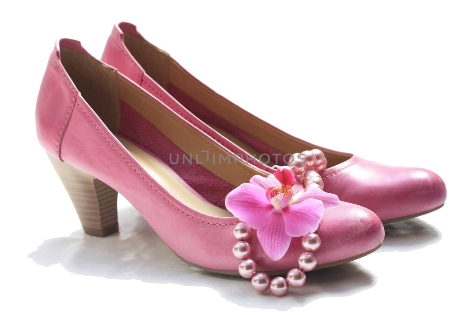 A pair of pink leather ladies shoes, a pearl necklace and a pink orchid