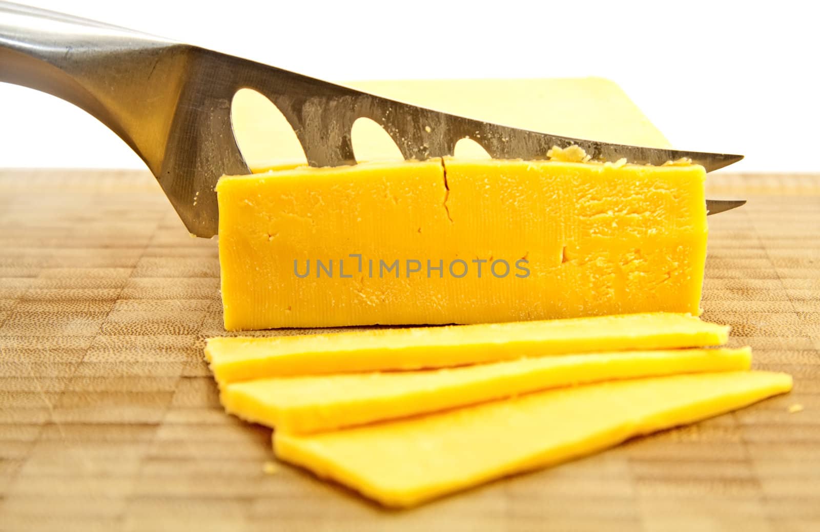 Slicing Gouda cheese with a knife on a wooden board