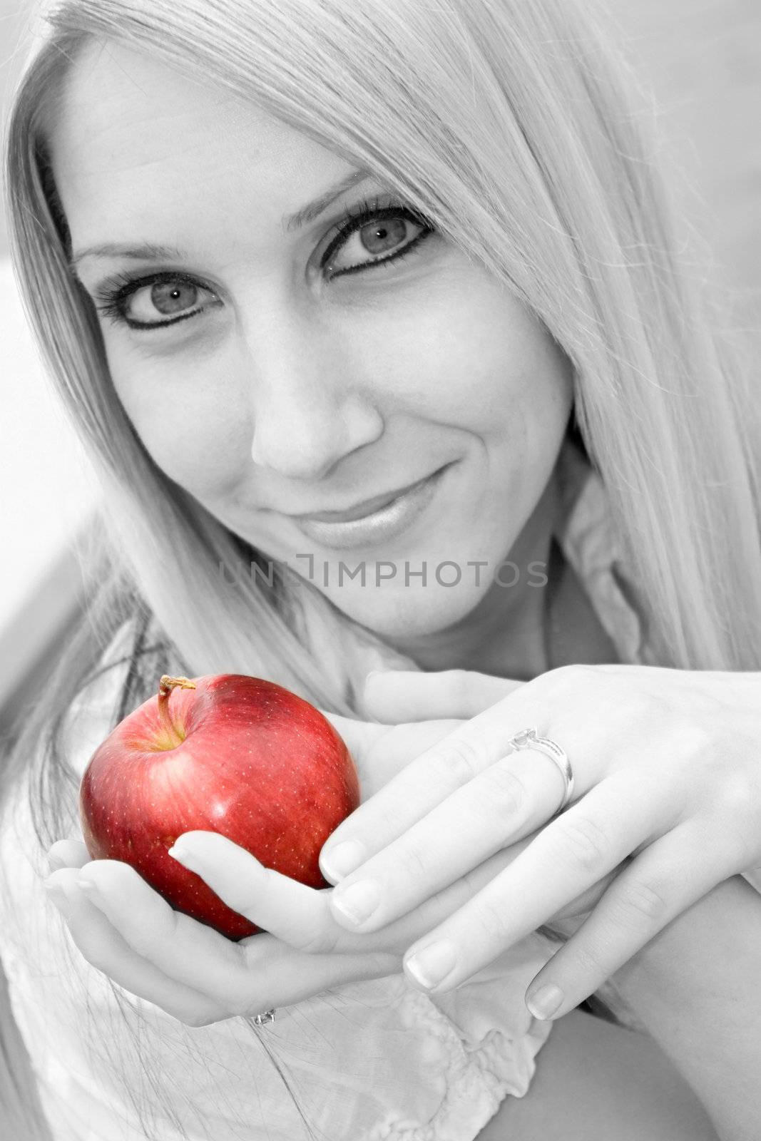 A young blond posing with an apple - black and white with selective color.