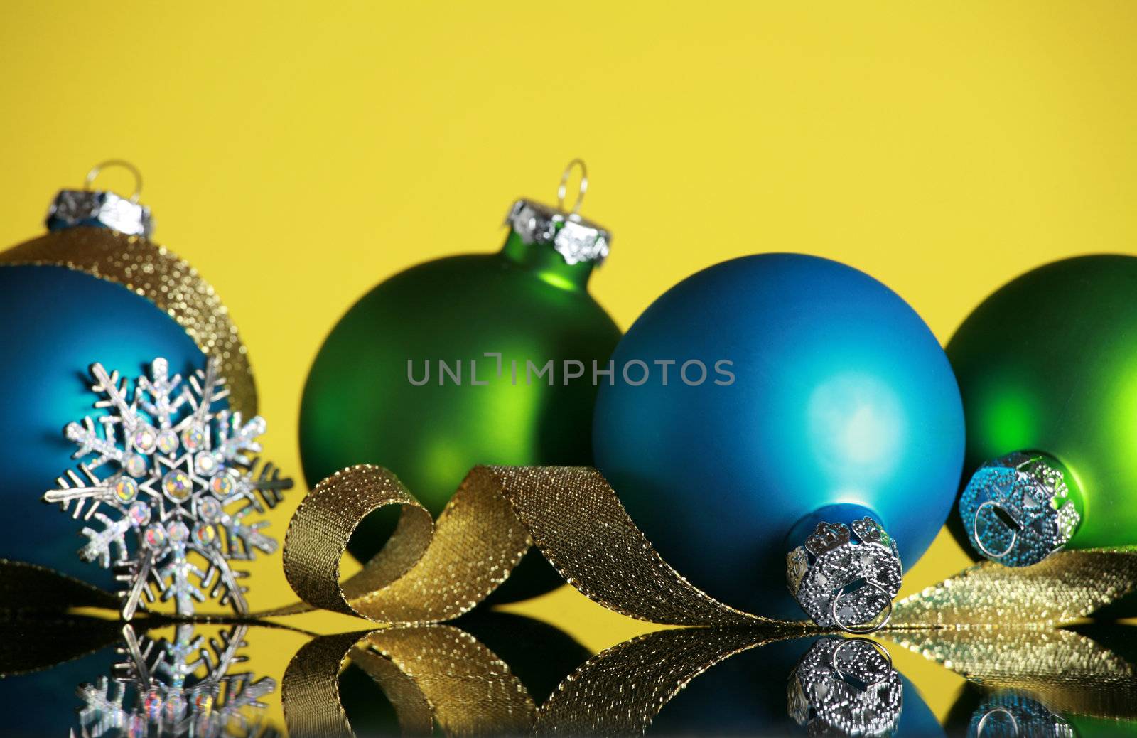 Christmas ornaments and snowflake on yellow background, focus on blue ball and gold ribbon