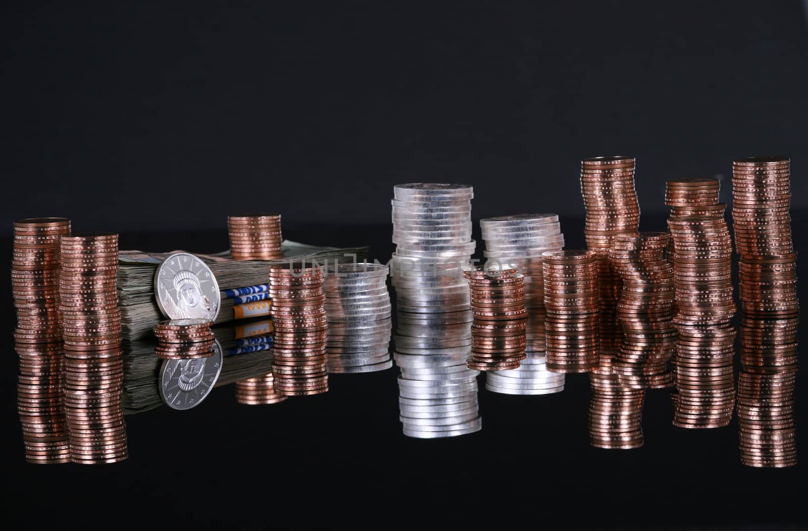 Stacks of silver and gold coins on black reflective surface