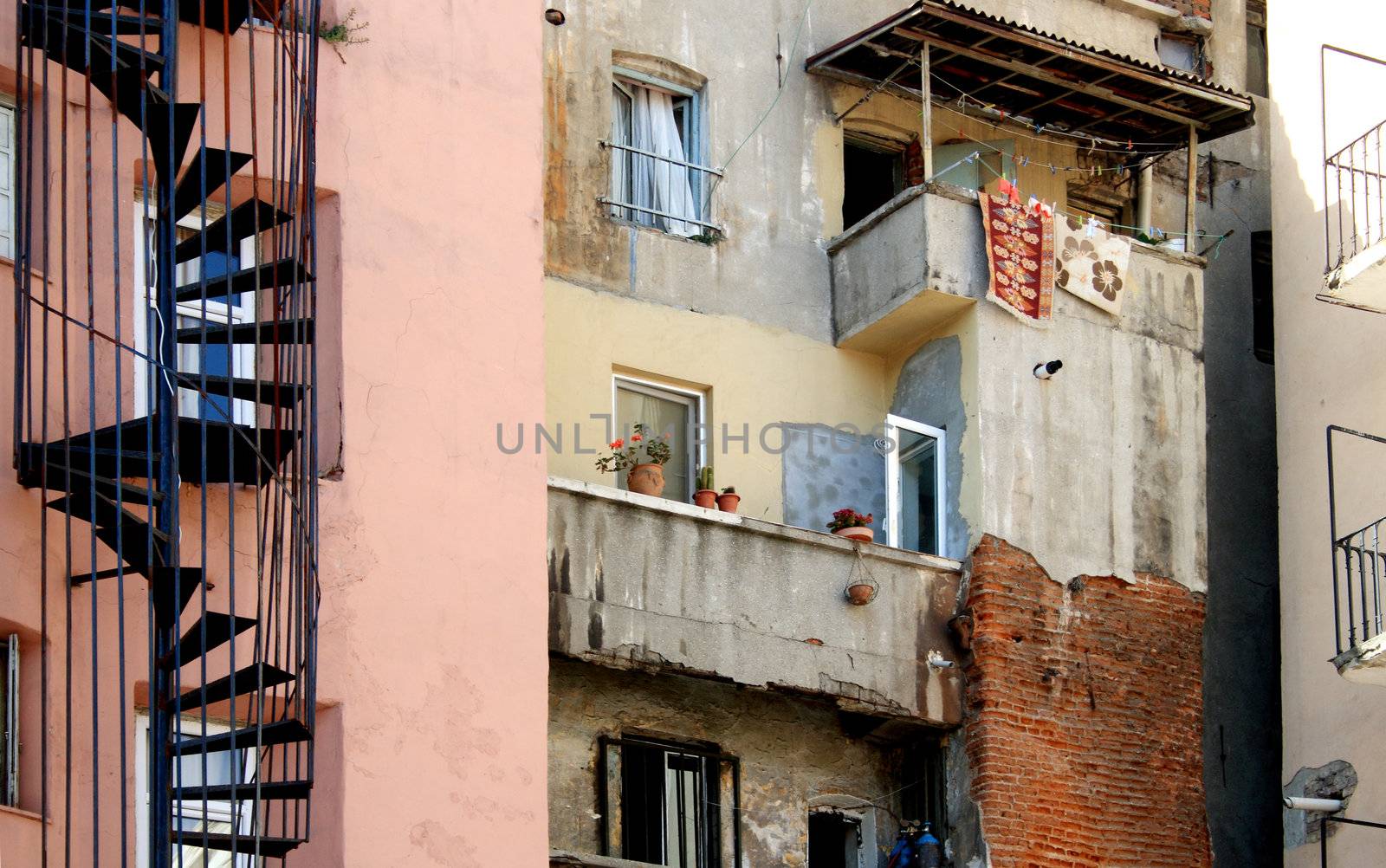 Underprivileged Areas Of City. Closeup of old building with spiral staircase flowerpots and small balcony