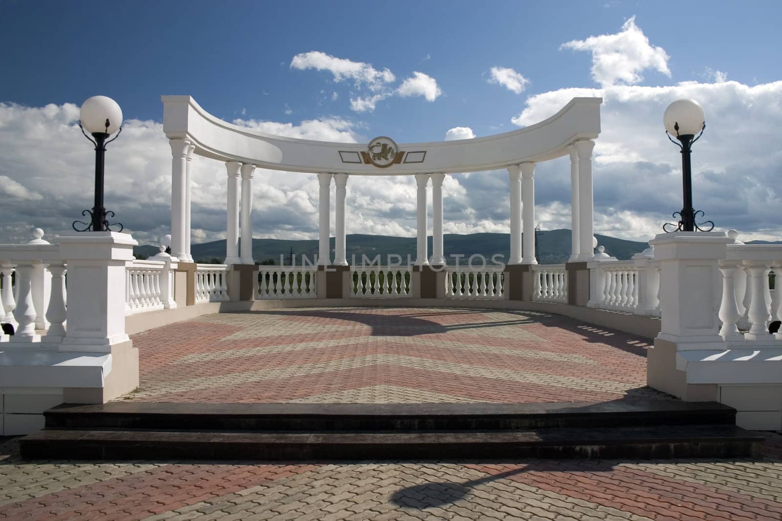 Balcony with white columns on a background of the sky with clouds.