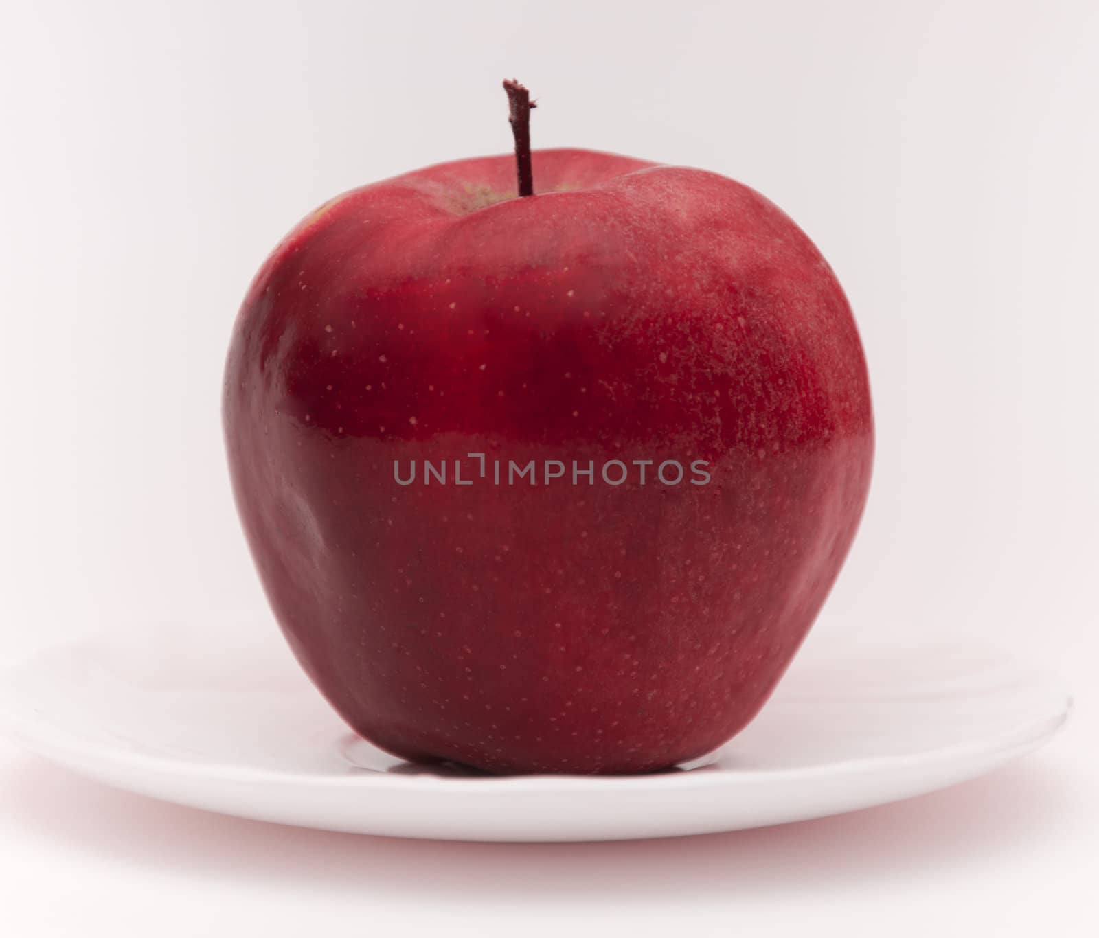 The isolated Red apple on white saucer