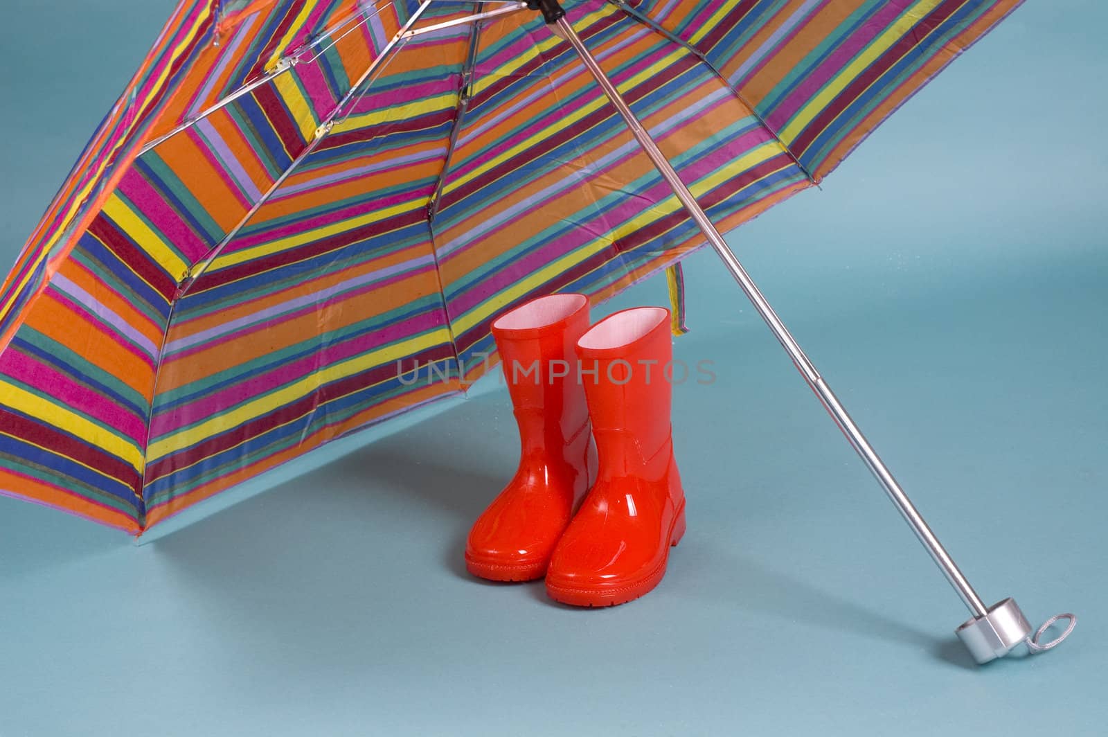 Red children rain boots and a colorful umbrella