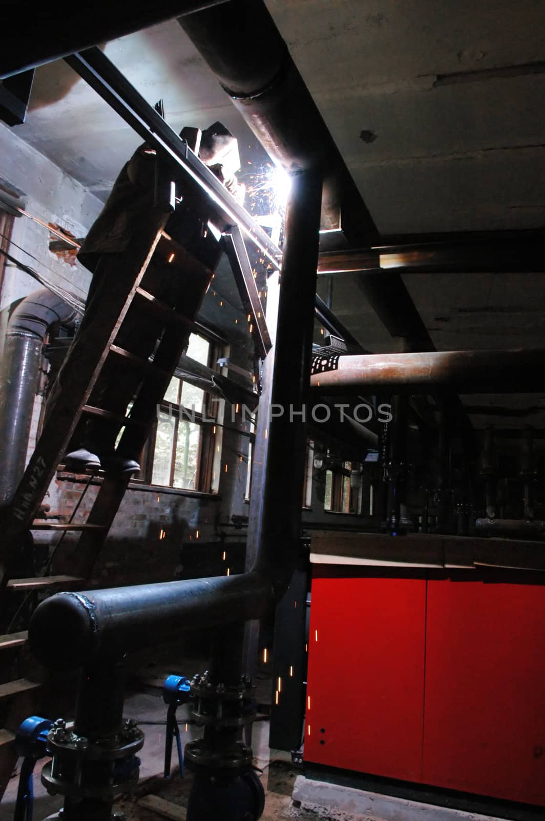 Welder welding a metal part in a dark industrial environment