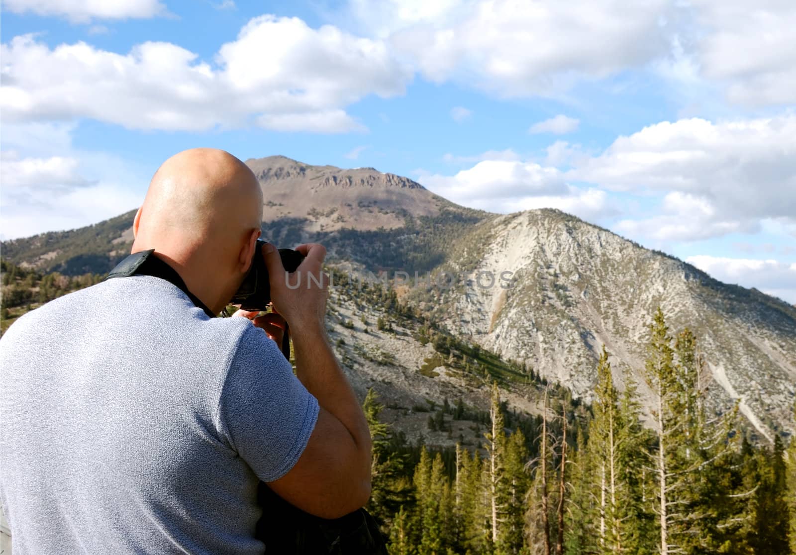 Male photographer shown shooting a picture of a mountain