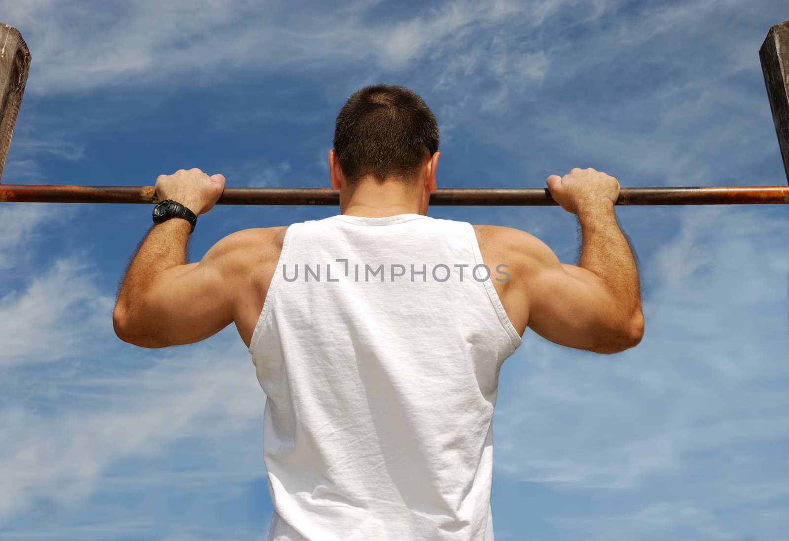 Reaching Goal: Strong Man Doing Pull-ups on a Bar in a Park