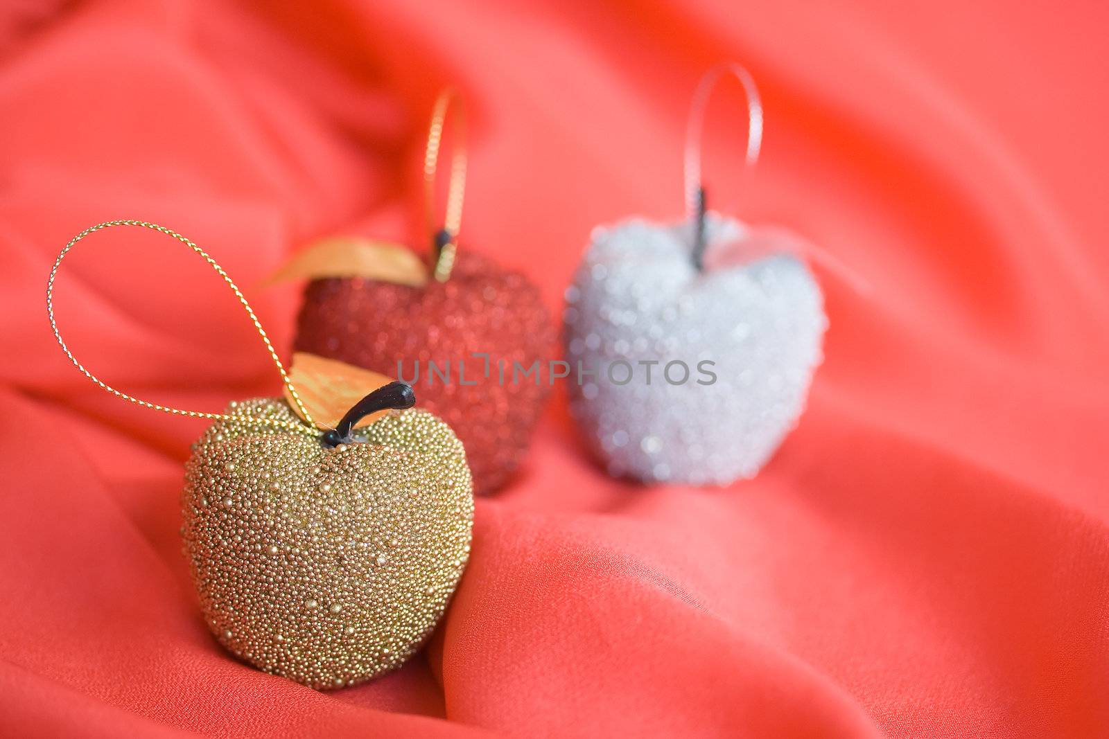 Three christmas tree apples on red background. Shallow depth of field