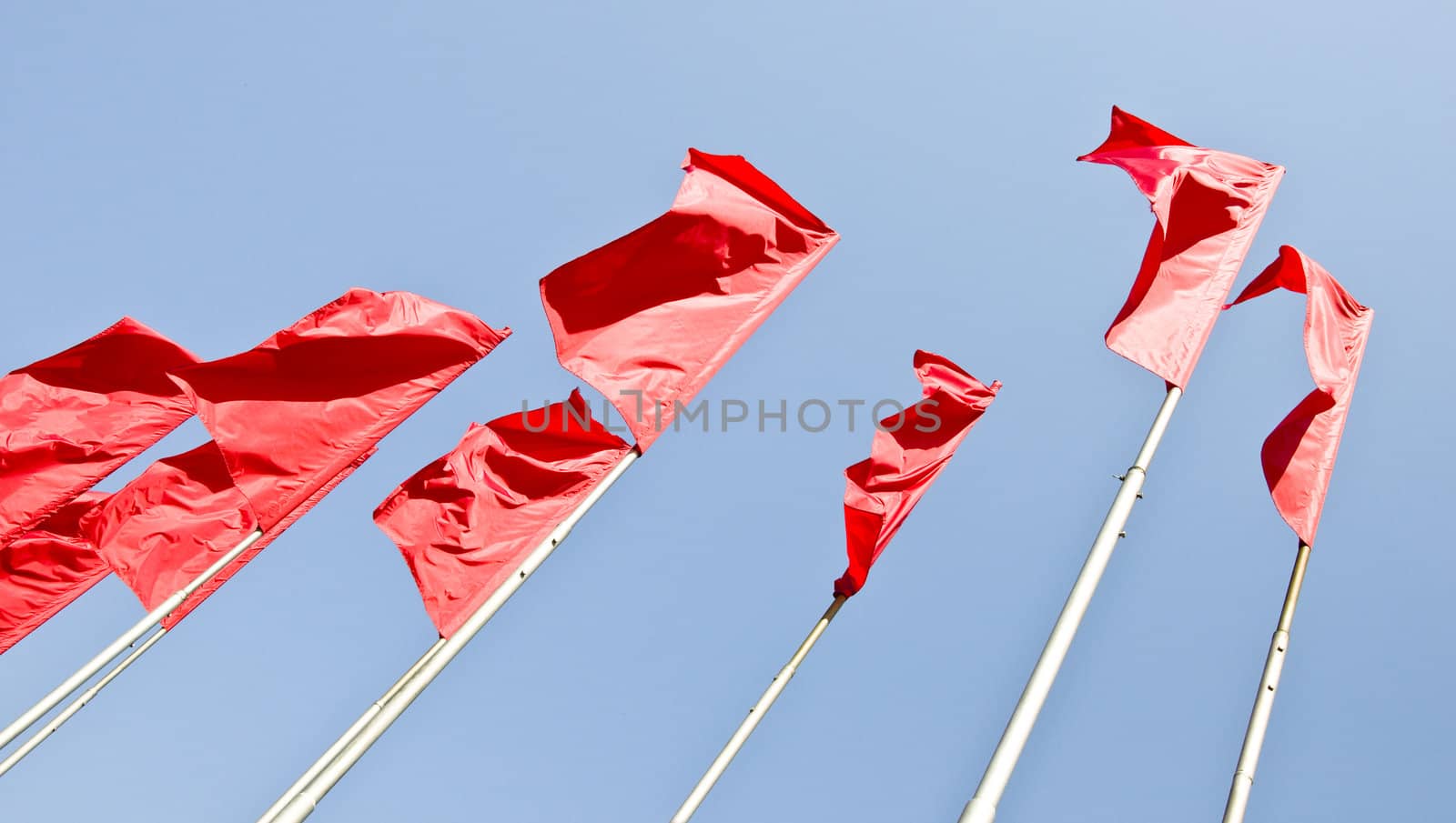 Red flags fluttered in the wind. Against the background of blue sky.