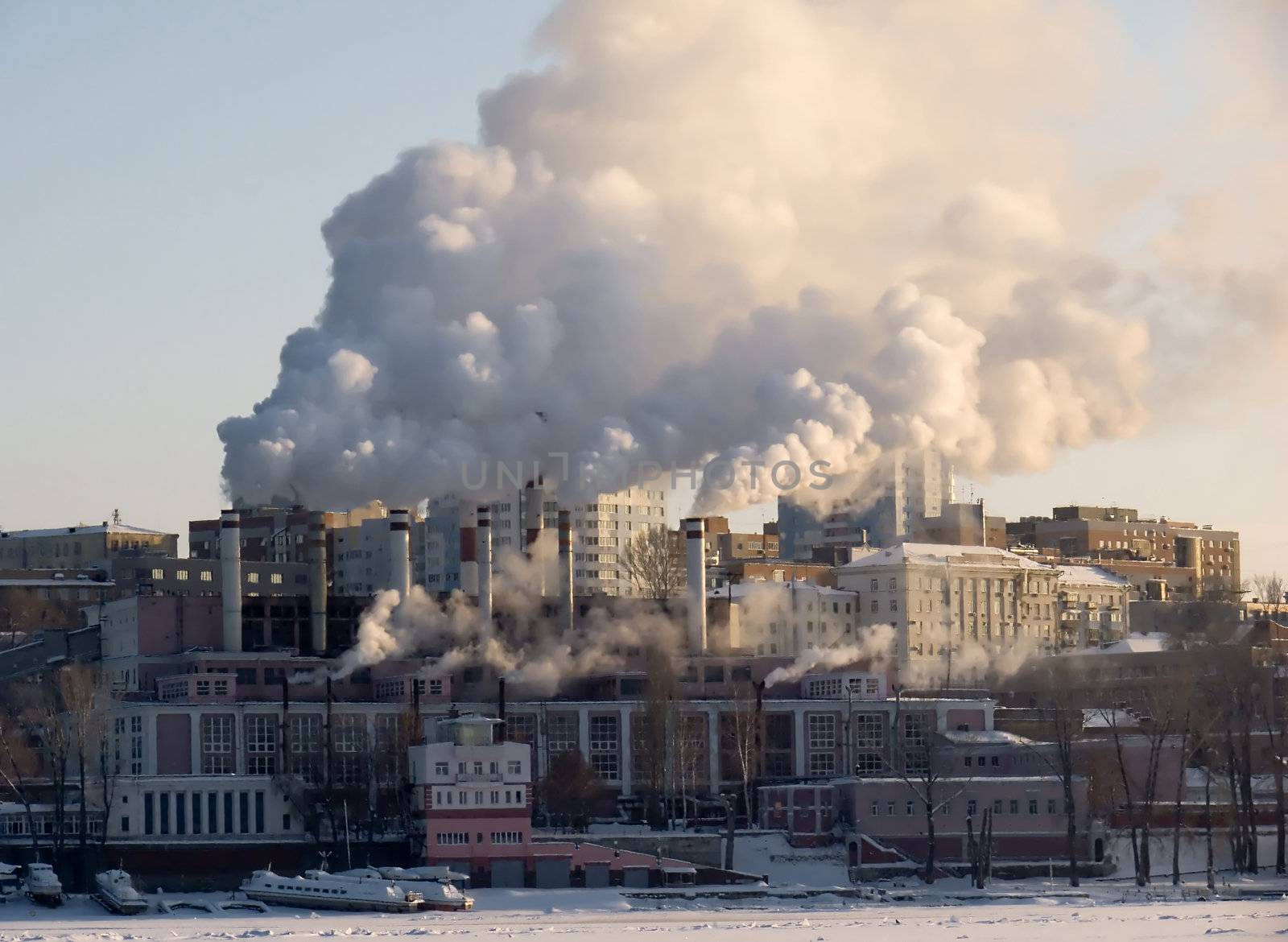 Winter urban landscape. From pipe factory fells smoke into the blue sky.