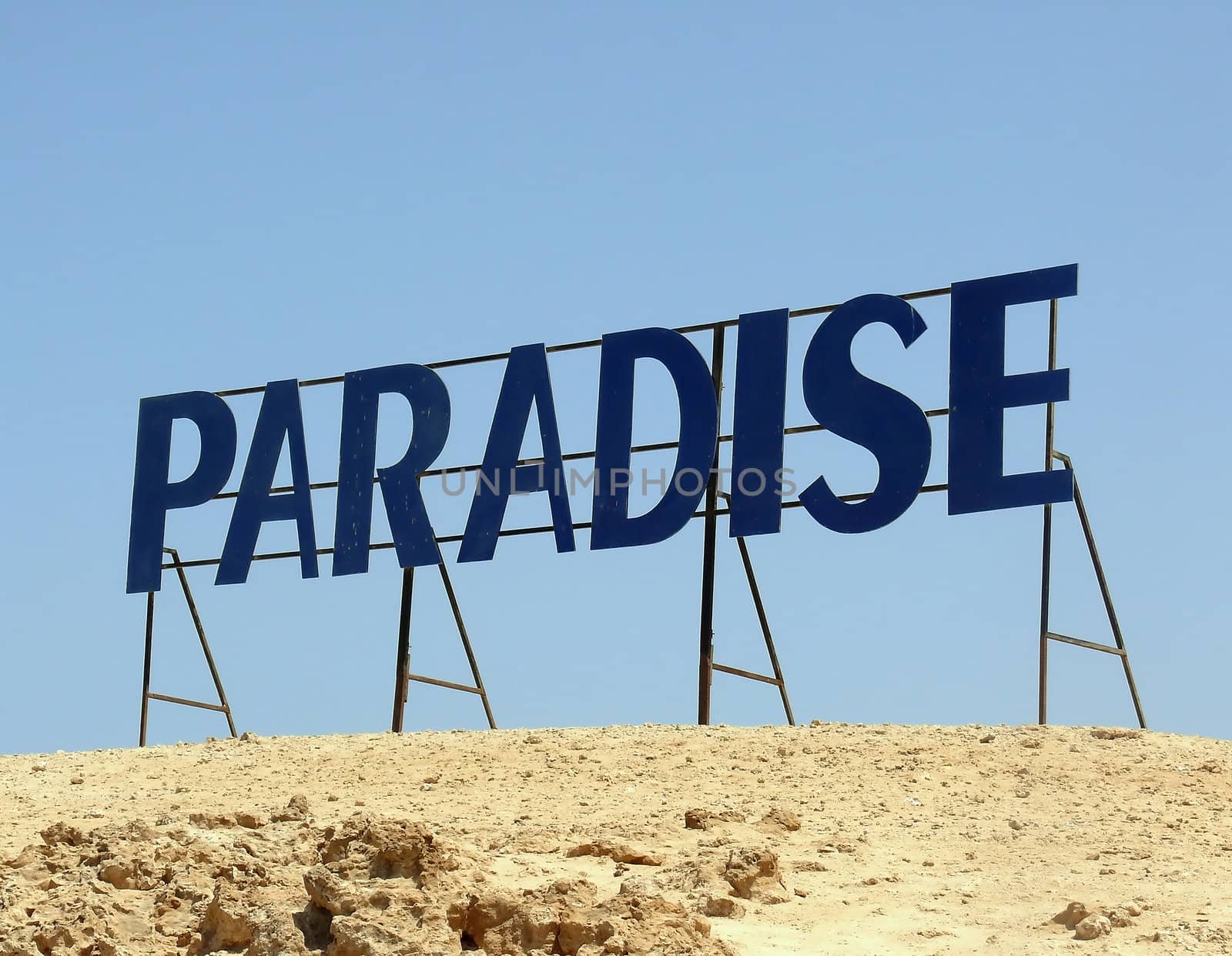 Paradise. Written letters on a background of blue sky in the desert.