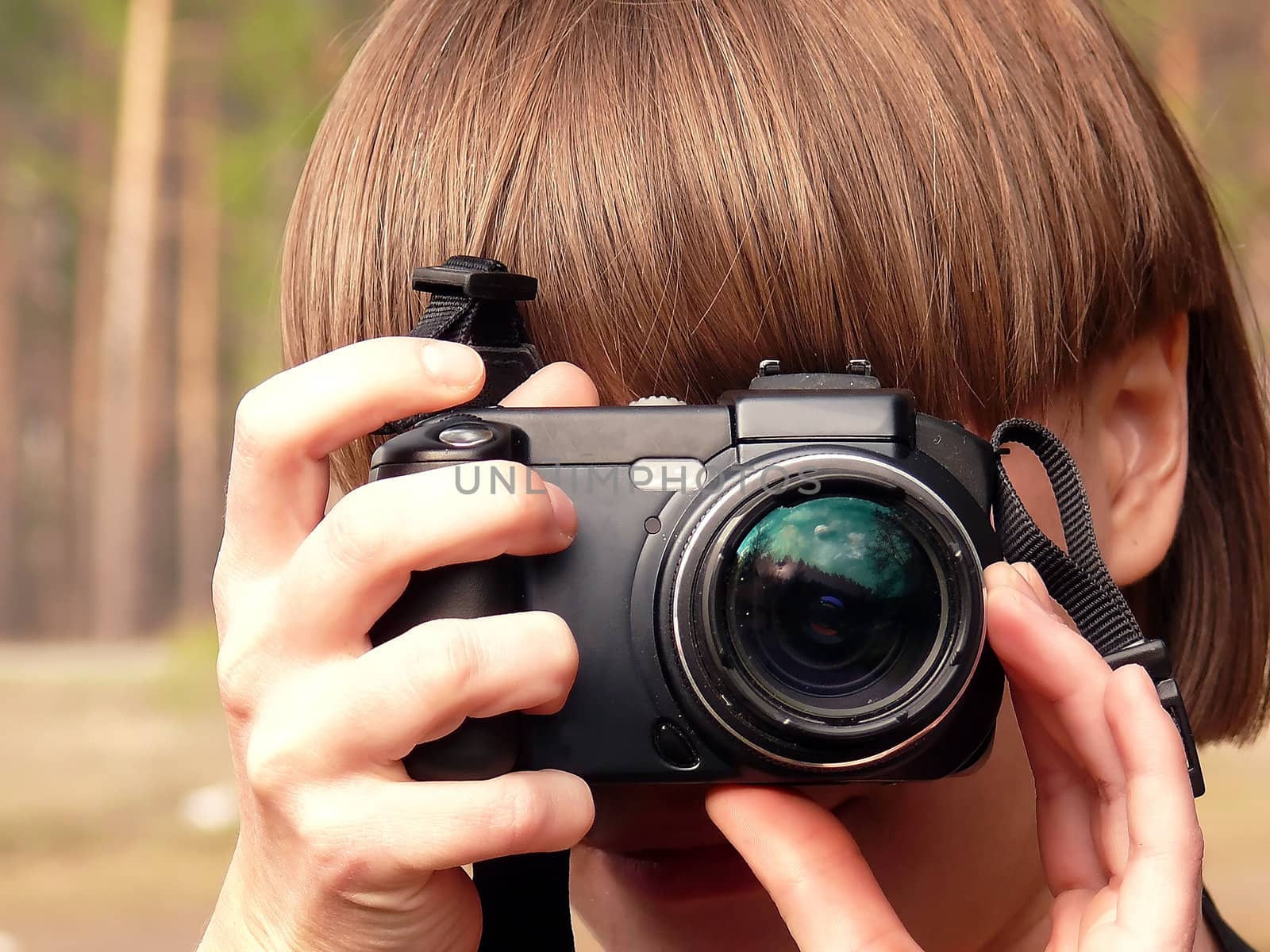 Young girl photographer looks through the viewfinder of the digital camera.