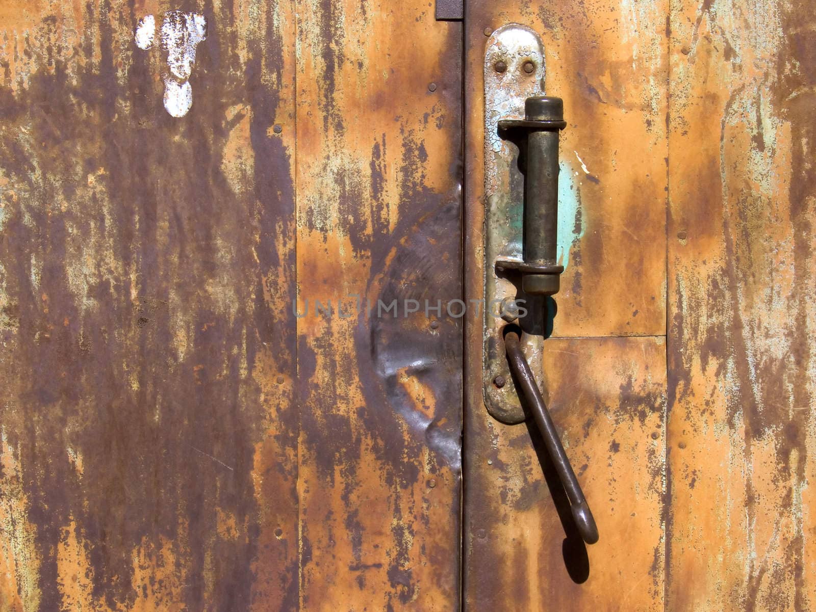 Old rusty door with a worn handle and lock.
