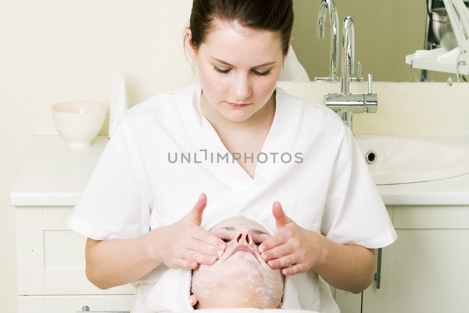 Lotion being massaged in during a facial at a beauty spa.