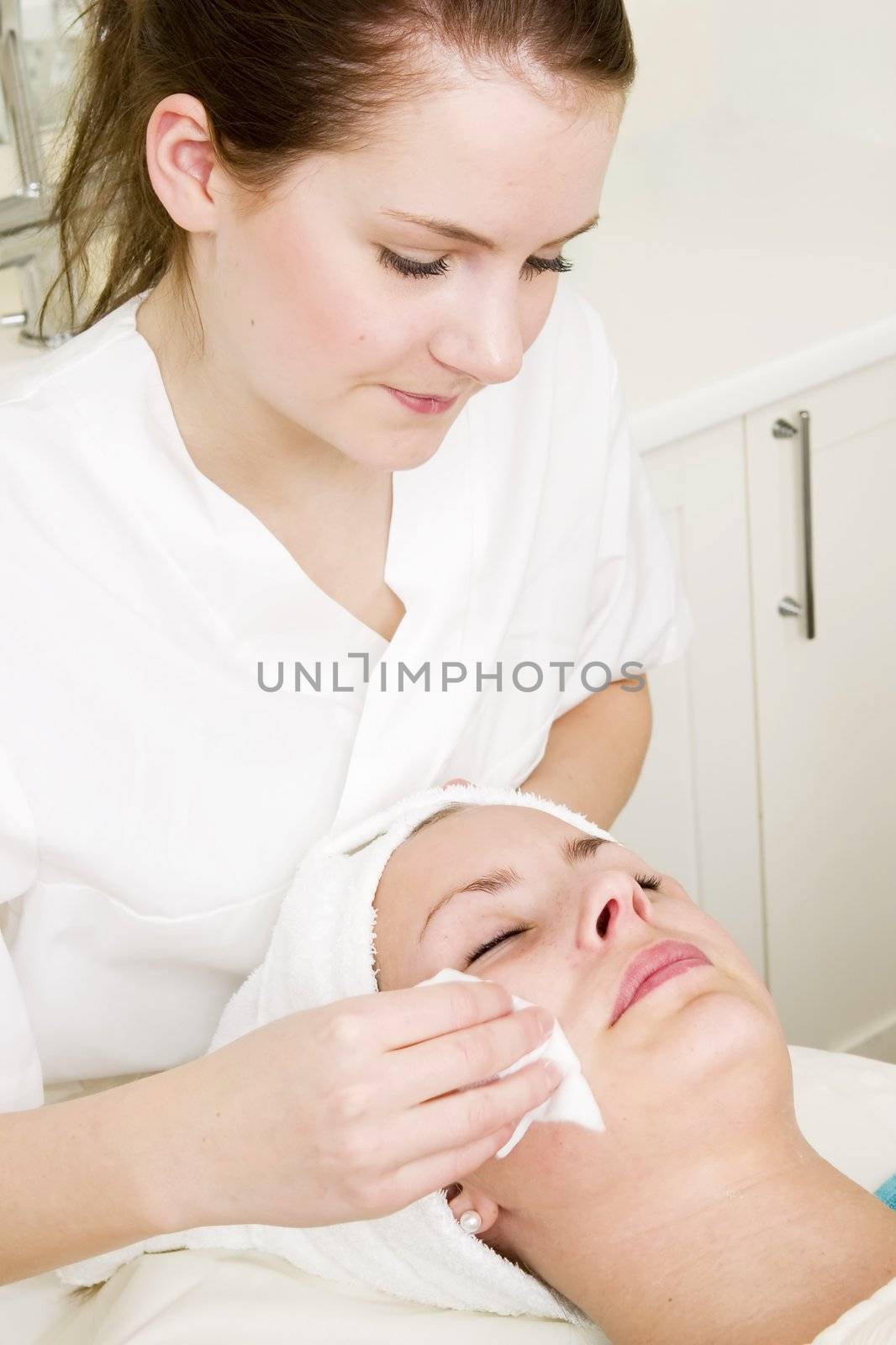 Lotion being wiped off during a facial at a beauty spa.