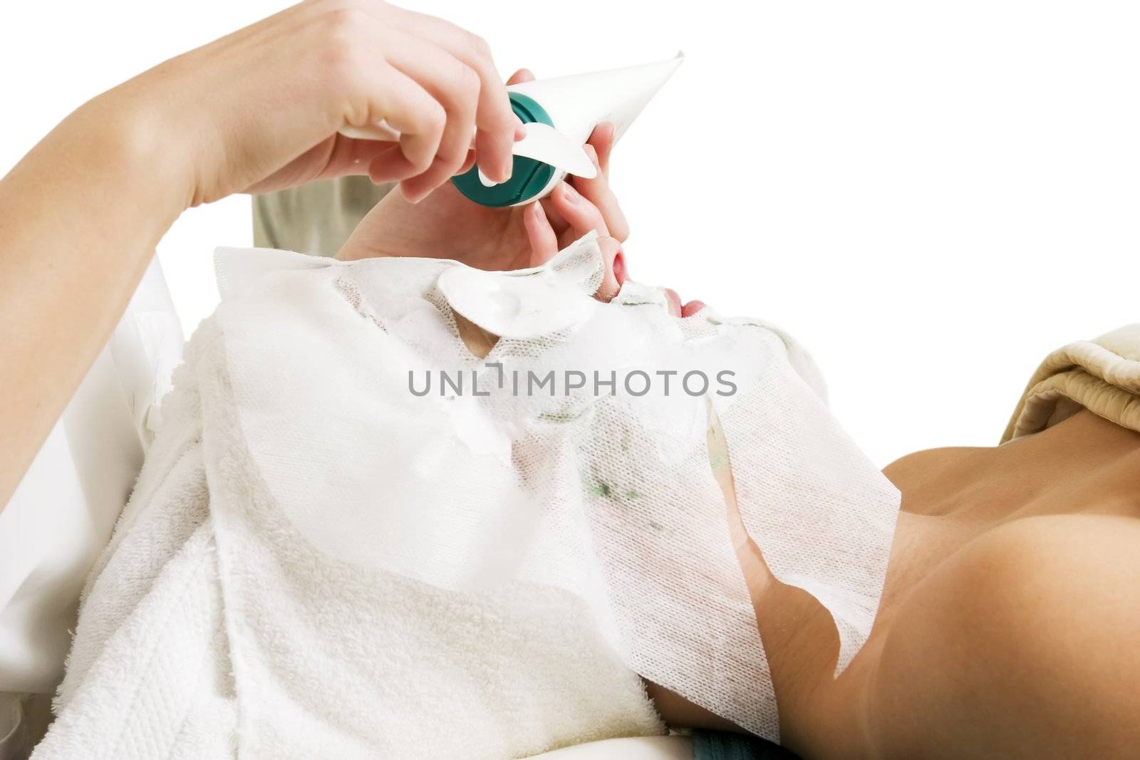 Lotion being applied to the face during a facial mask at a beauty spa.