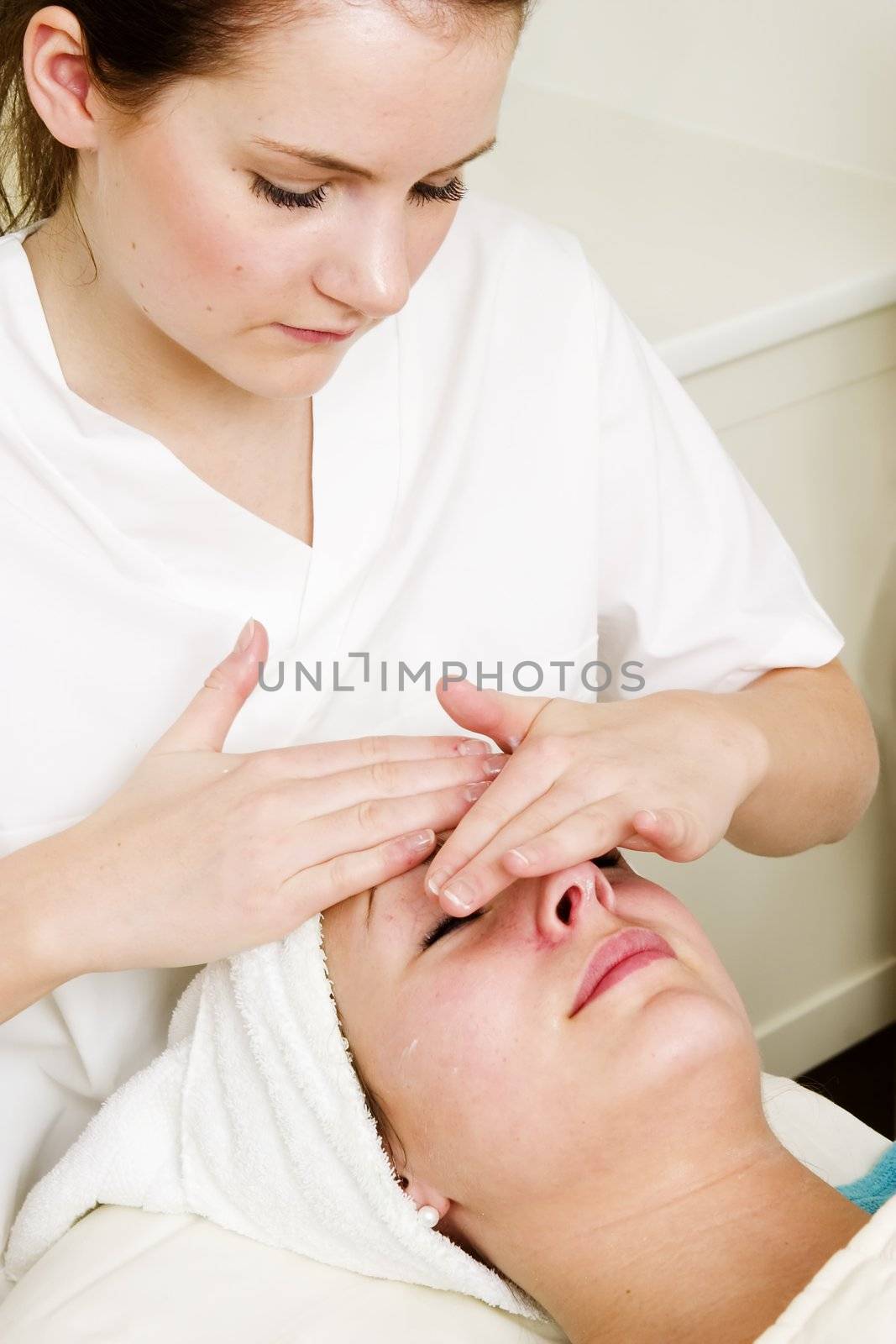 A woman receiving a facial massage at a beauty spa.