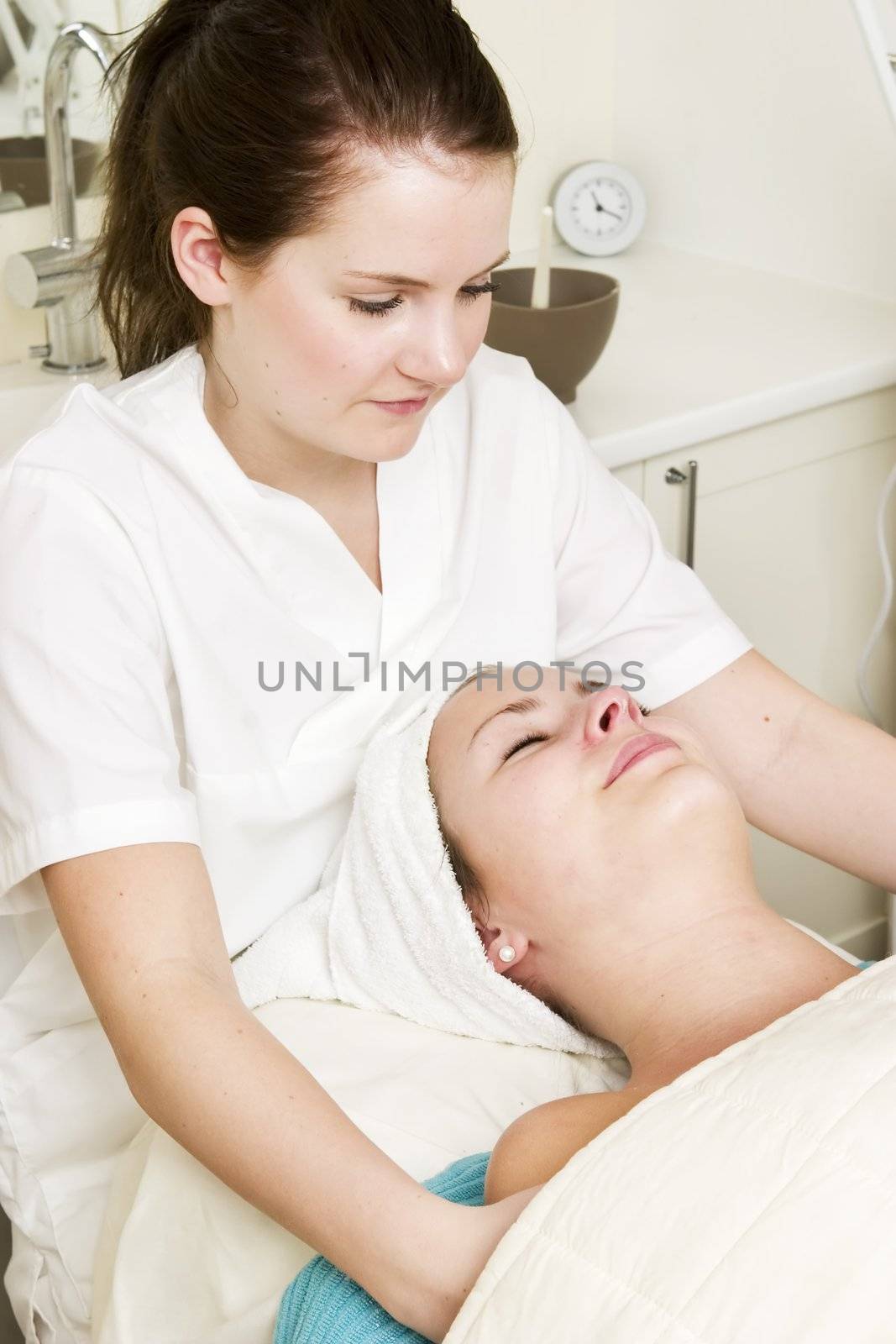 A woman at a day spa, recieving a facial and should massage